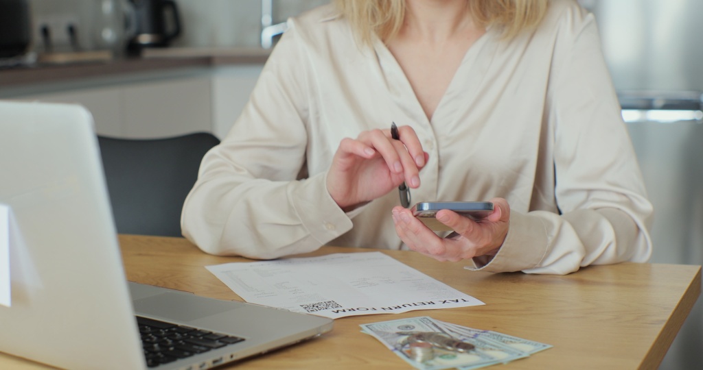 close-up-woman-fills-out-paper-document-counts-phone-screen-young-woman-is-writing-tax-return-form-looking-laptop-table-home-room.jpg ноутбук
